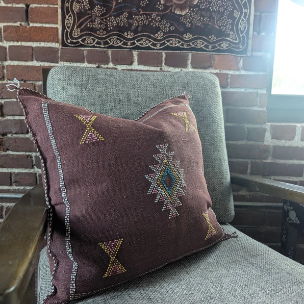 Close-up of Nadia Moroccan cactus silk throw pillow in rich brown, showing detailed handwoven embroidery with geometric motif