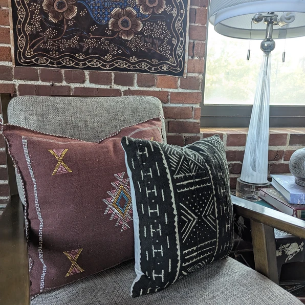 Nadia Moroccan cactus silk throw pillow in brown with colorful embroidery, styled with a black African mudcloth pillow on a g