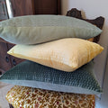 Blue yellow and green italian velvet throw pillows stacked together on a vintage floral chair in a living room