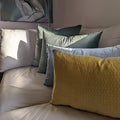 yellow, blue, and green velvet contemporary pillow cushions from italy arranged together on white leather sofa in living room