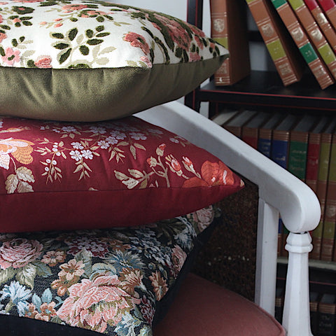 three woven european throw pillows with flower designs stacked in reading nook chair