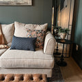 two french pillow cushions on couch in moody living room next to mirror and side table