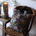 Decorative throw pillow with French floral tapestry design in wicker chair