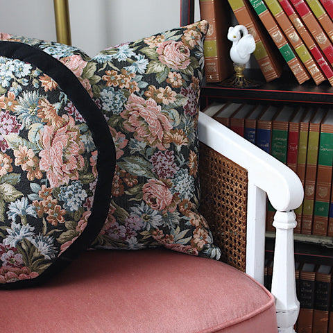 two french pillows with woven floral designs in chair next to bookshelf