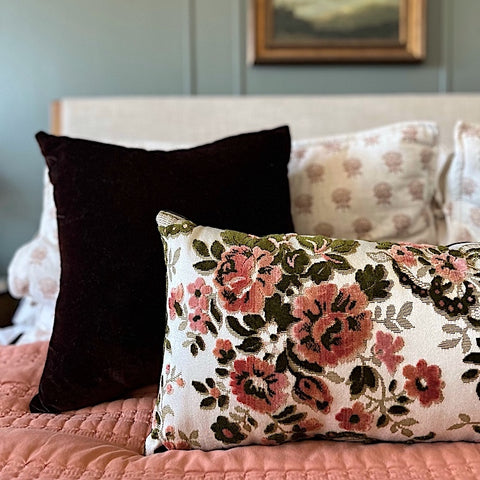 pink and green velvet floral lumbar pillow cushion on bed layered with other pillows